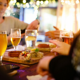 Glasses of beer and plates of pinchos on a table surrounded by customers