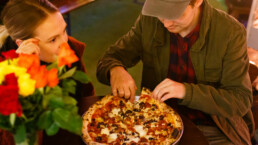 Two customerCouple eating a pizza in the Franciscan Well beer garden where table booking is not required