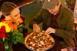 Two customerCouple eating a pizza in the Franciscan Well beer garden where table booking is not required