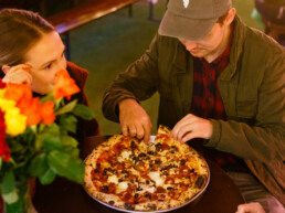 Two customerCouple eating a pizza in the Franciscan Well beer garden where table booking is not required