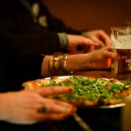 customers eating pizza at Franciscan Well where the table booking policy is walk-in only for groups of under 10 people