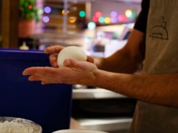 Pizzaiolo rolling a ball of pizza dough in his hands