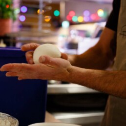 Pizzaiolo rolling a ball of pizza dough in his hands