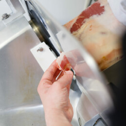 Close up of staff member slicing Parma ham with a meat slicer