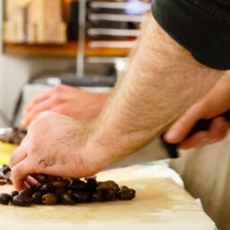 Close-up of staff-member's hands chopping olives