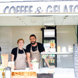 One female & one male members of Pompeii Pizza staff standing in the Coffee & Gelato food trailer in Waterville