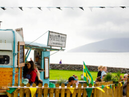 Customers at the Coffee & Gelato food trailer in Waterville, with the Pompeii Pizza mobile pizzeria trailer & sea view in the background