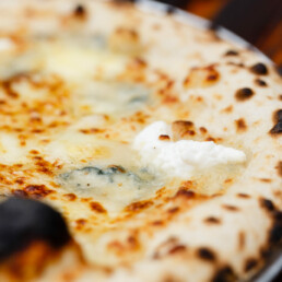 Close-up of Quattro Formaggio pizza in a metal tray on a wooden table