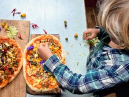 child putting finishing touches on pizza made at home with pompeii pizza kit