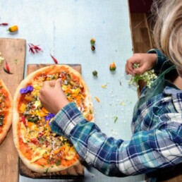 child putting finishing touches on pizza made at home with pompeii pizza kit